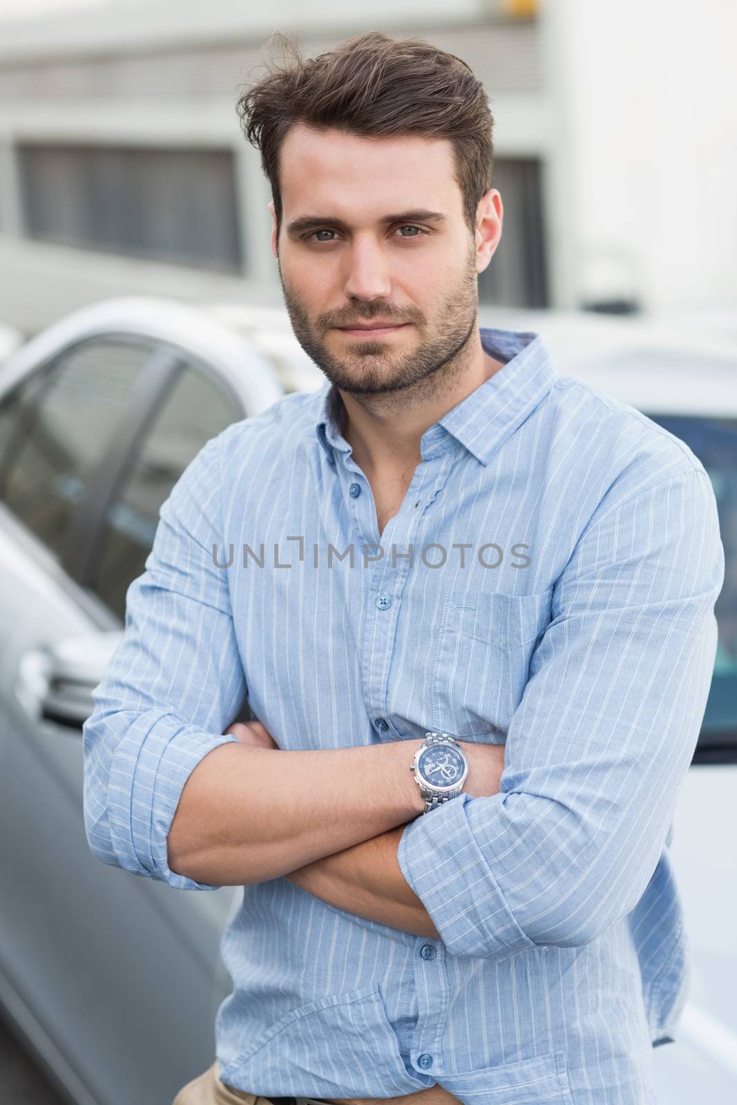 Young man smiling at camera outside his car