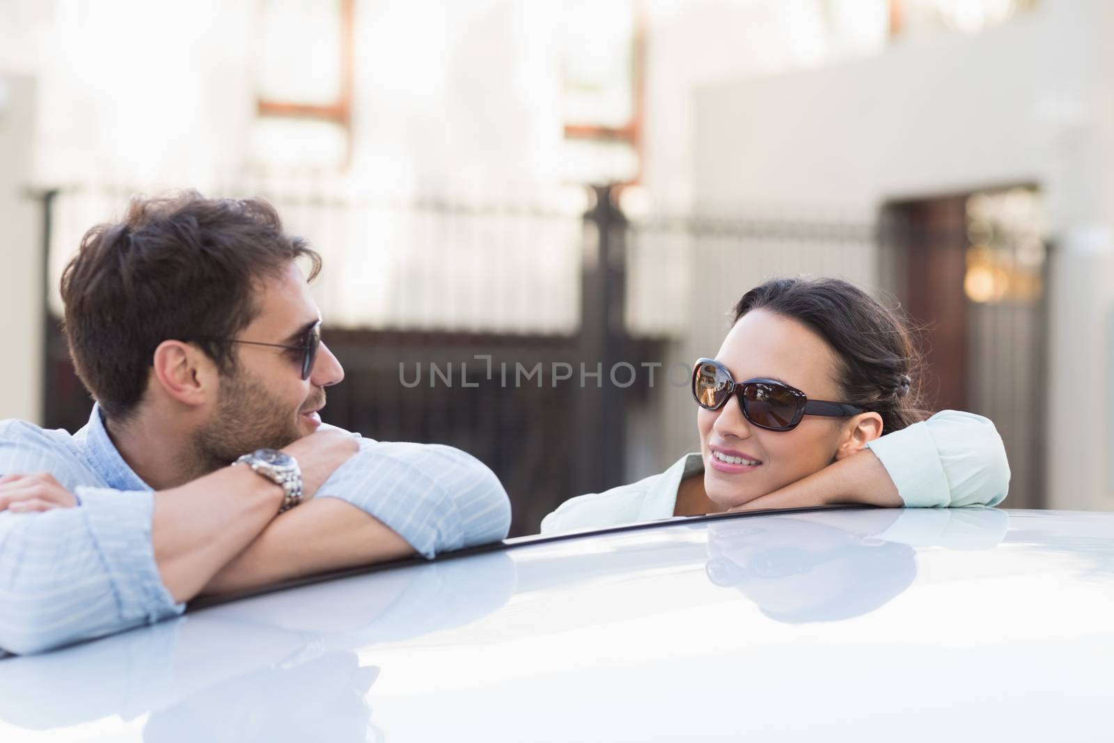Young couple smiling at each other outside their car