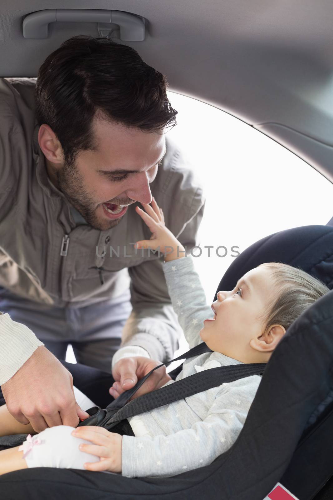 Father securing baby in the car seat by Wavebreakmedia