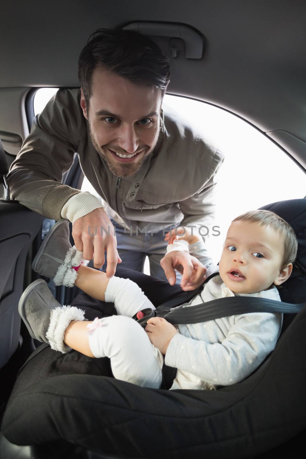 Father securing his baby in the car seat in his car