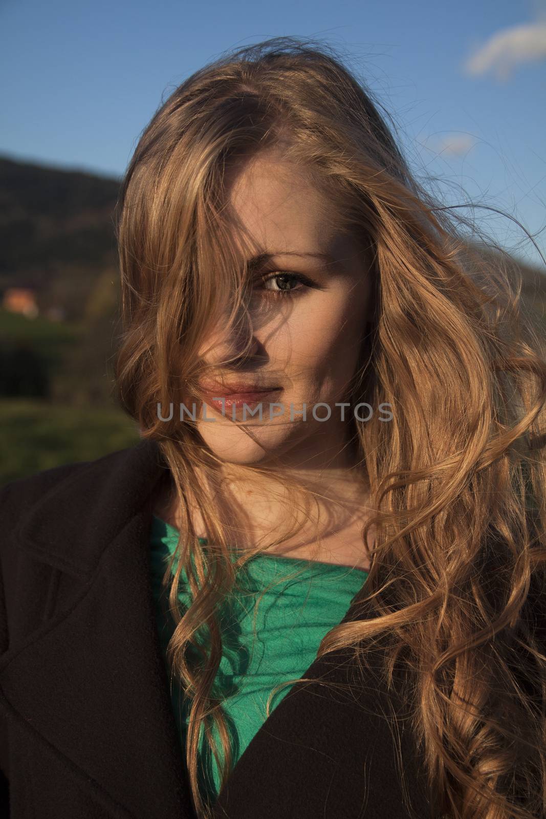 Young long-haired curly blonde woman presented beautiful natural long curly blond hair