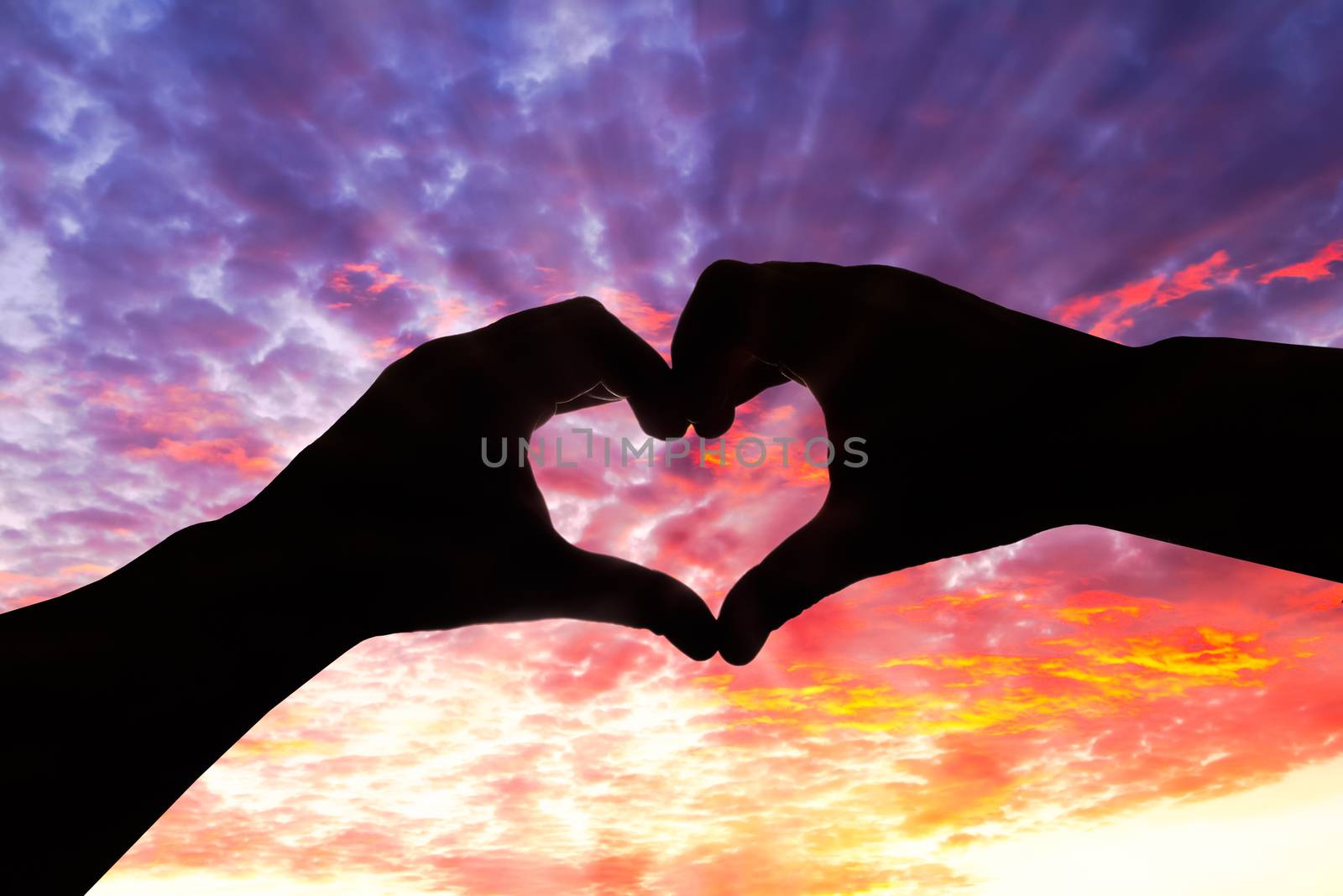 Silhouette hand in heart shape and beautiful sky by gianliguori