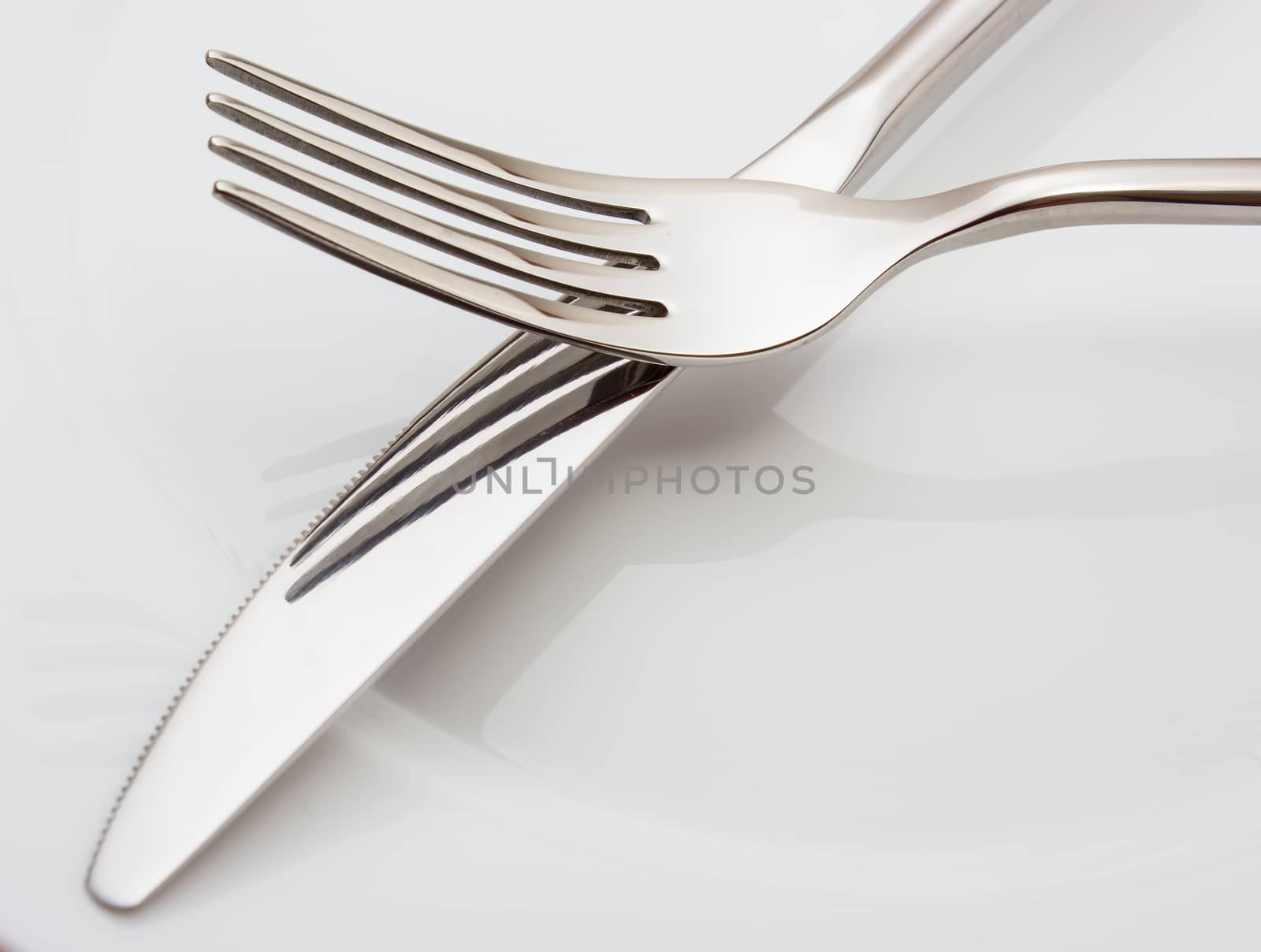 Silverware: fork and knife on white empty plate