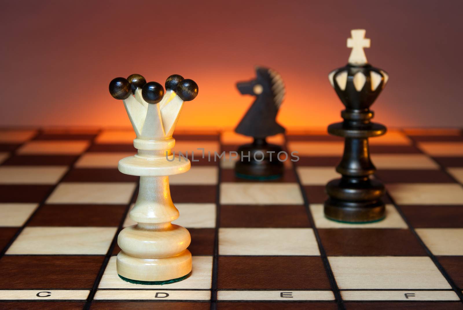 Chess (queen, king and a horse) on a chess board. An art dark background.