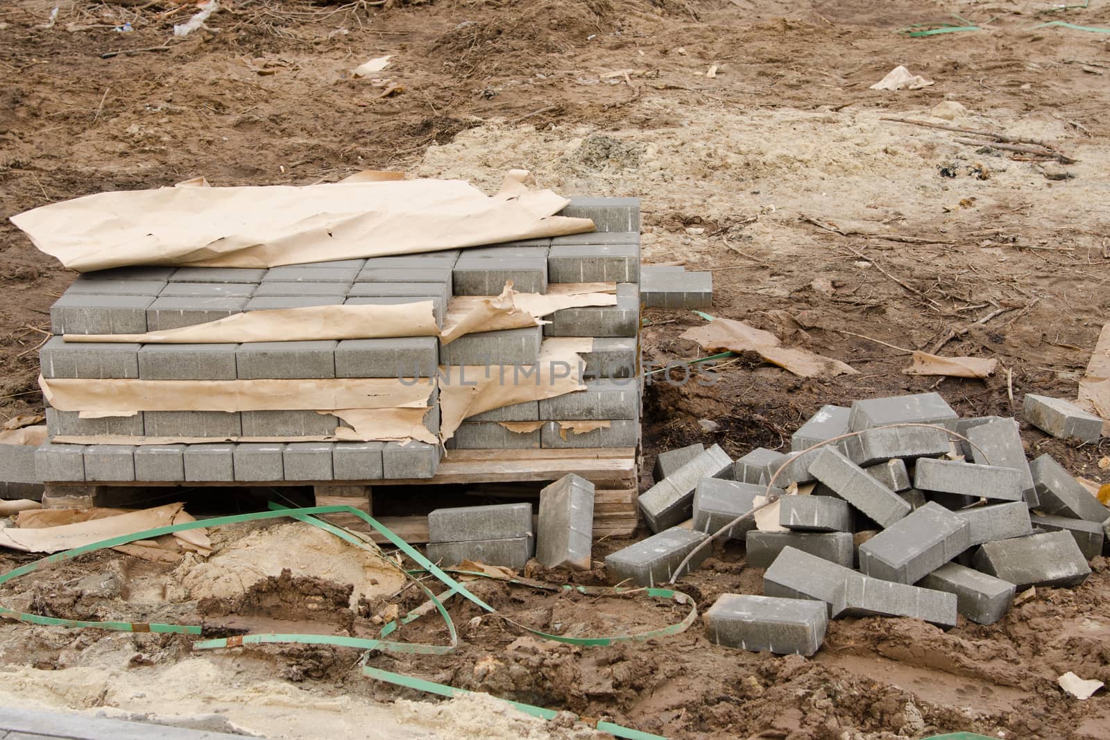Elements of paving slabs stacked on a pallet in a stack and heap on the ground lying around on the street
