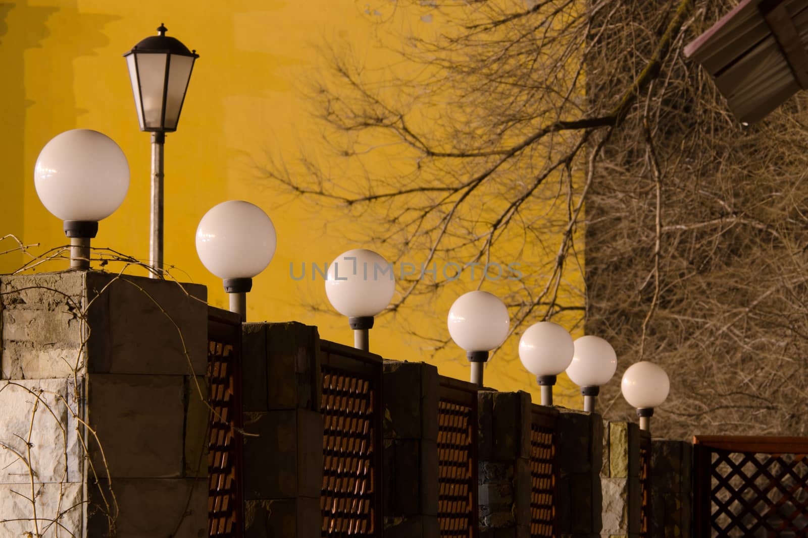 Number of round street lamps not burning on the fence in the evening