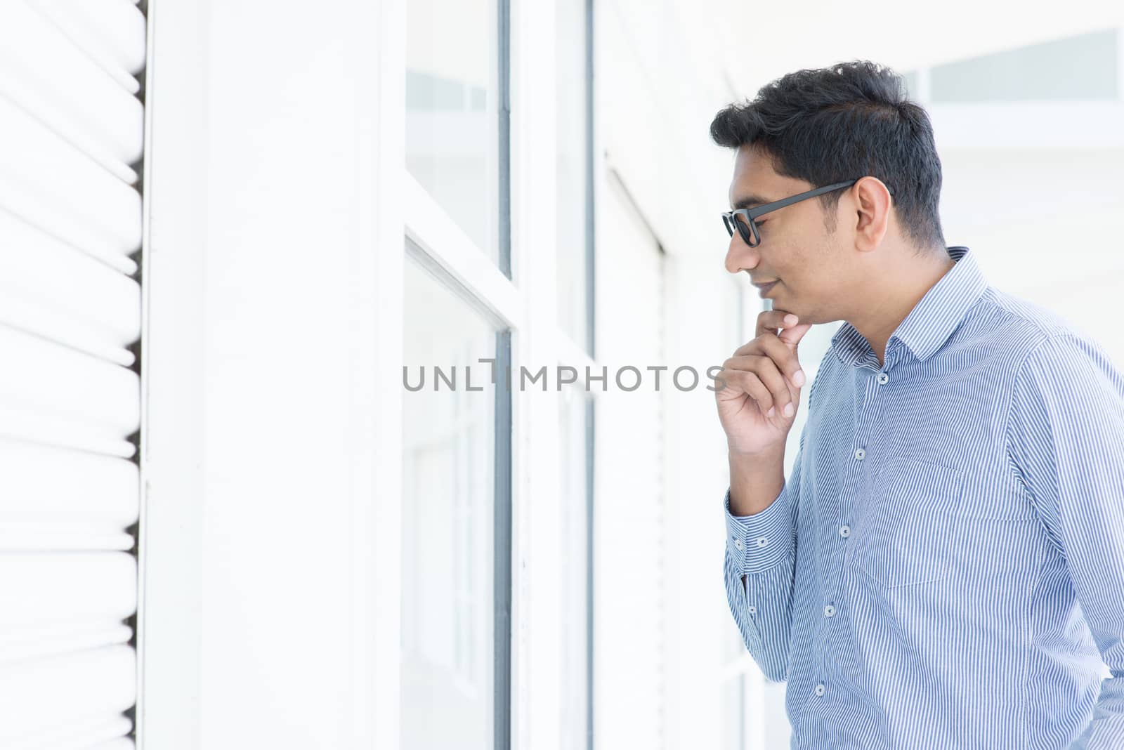 Young man looking through the window and thoughtful.