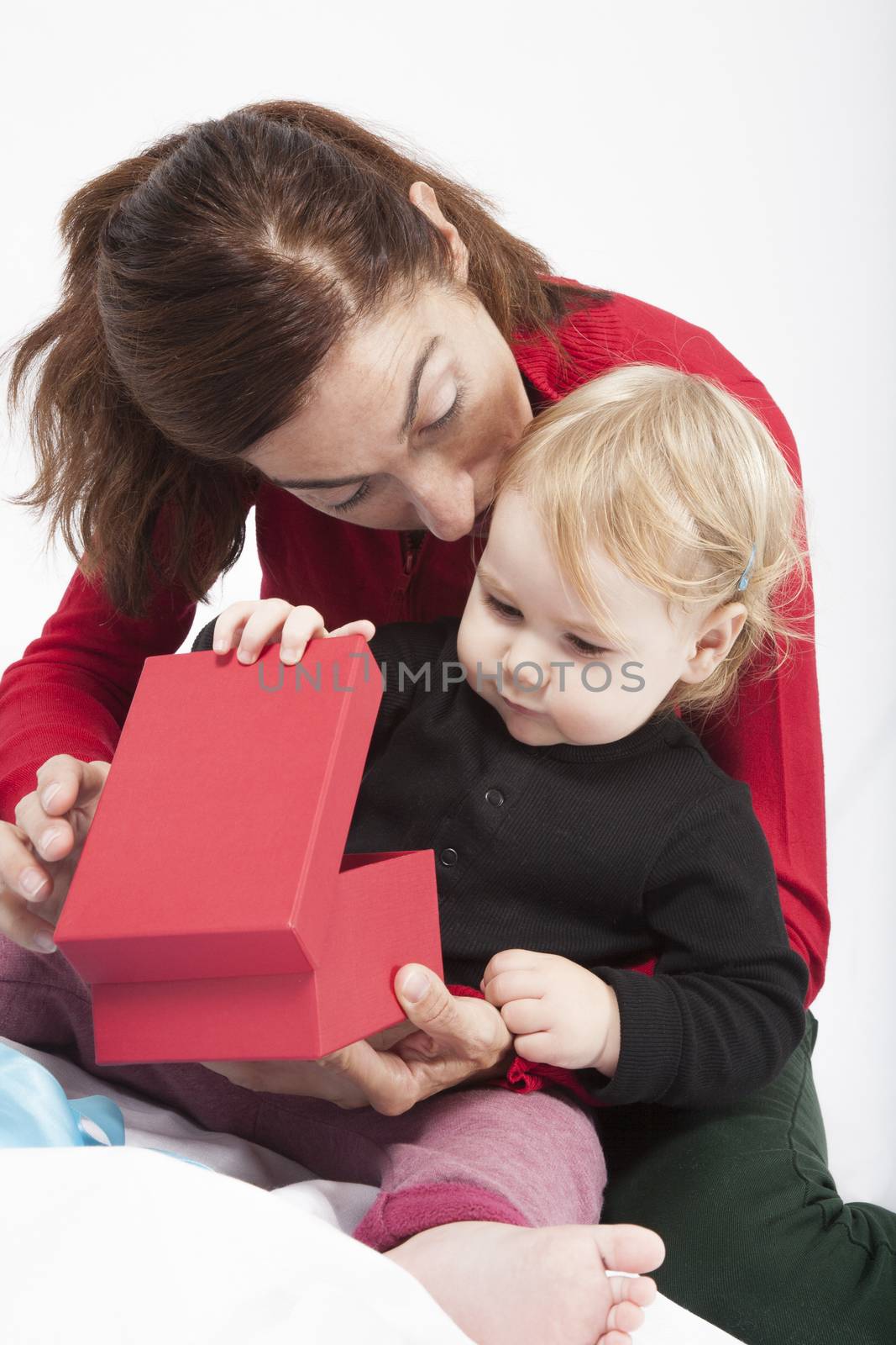 one year age caucasian blonde baby black shirt with brunette woman mother cardigan green trousers opening red box gift on white background