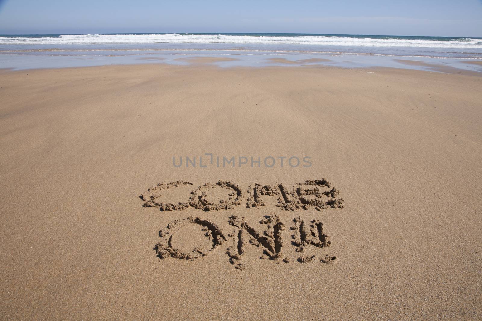 come on word written on brown sand ground low tide beach ocean seashore in Spain Europe
