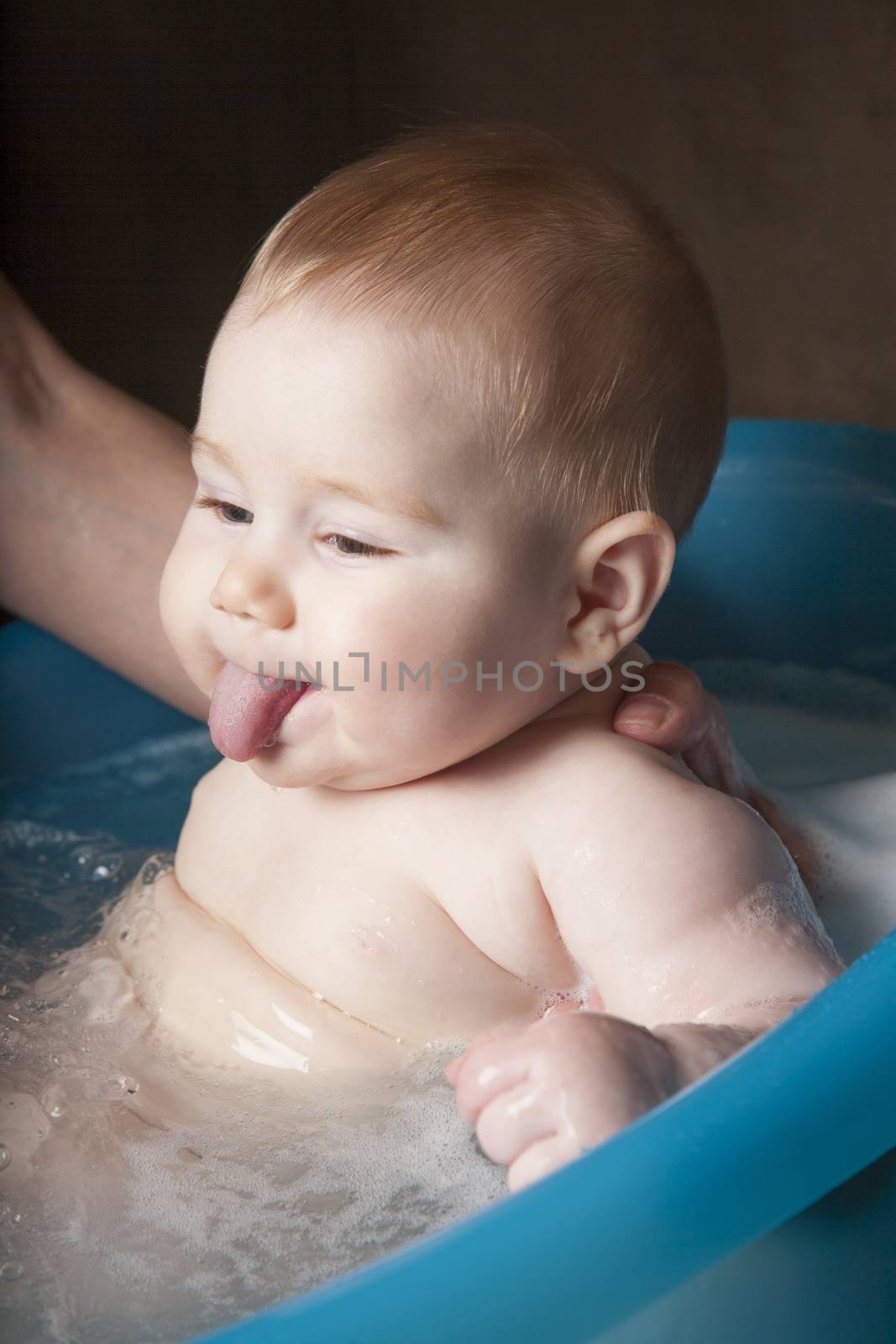 sticking out tongue baby washing by quintanilla