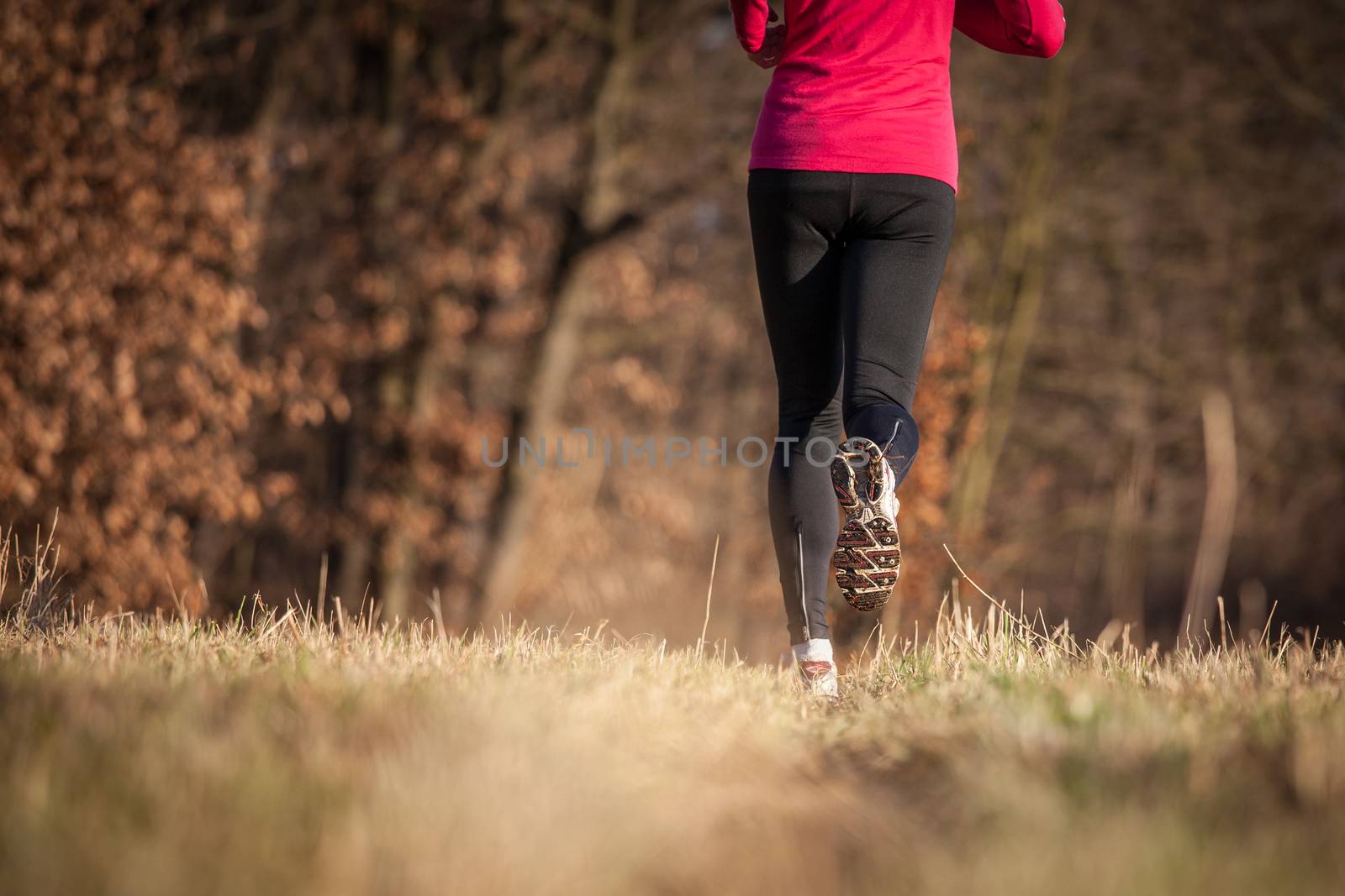 Young woman running outdoors on a lovely sunny winter/fall day (motion blurred image)