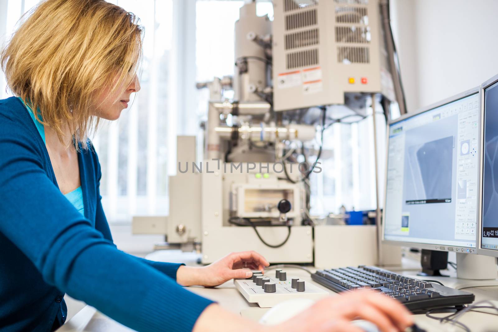 Pretty, female researcher using a microscope in a lab by viktor_cap