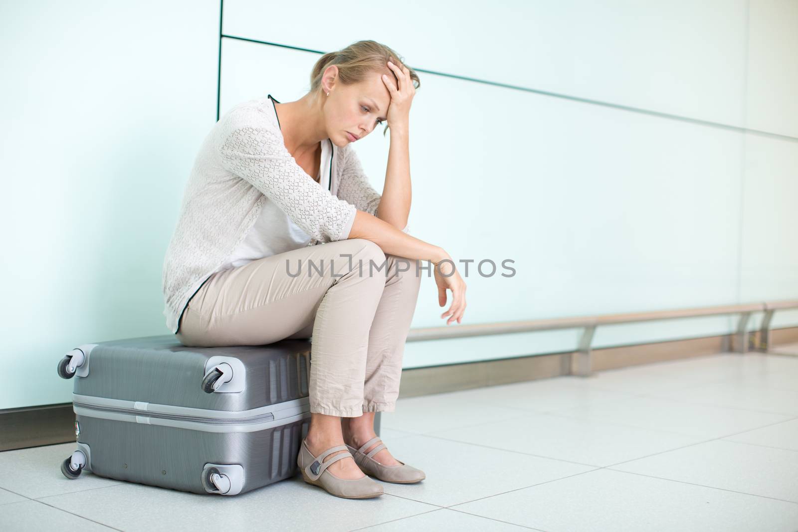 Young, female frustrated passenger at the airport, waiting desperately for her delayed flight (color toned image; shallow DOF)