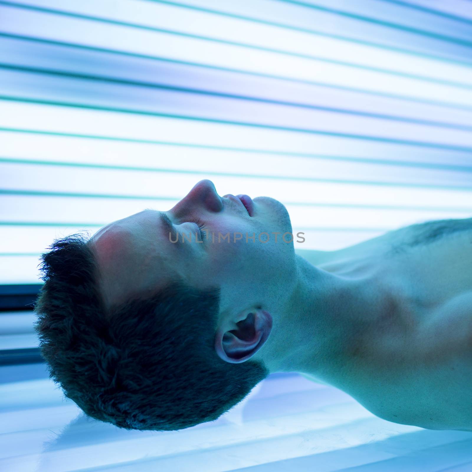 Handsome young man relaxing  in a modern solarium session in a modern by viktor_cap