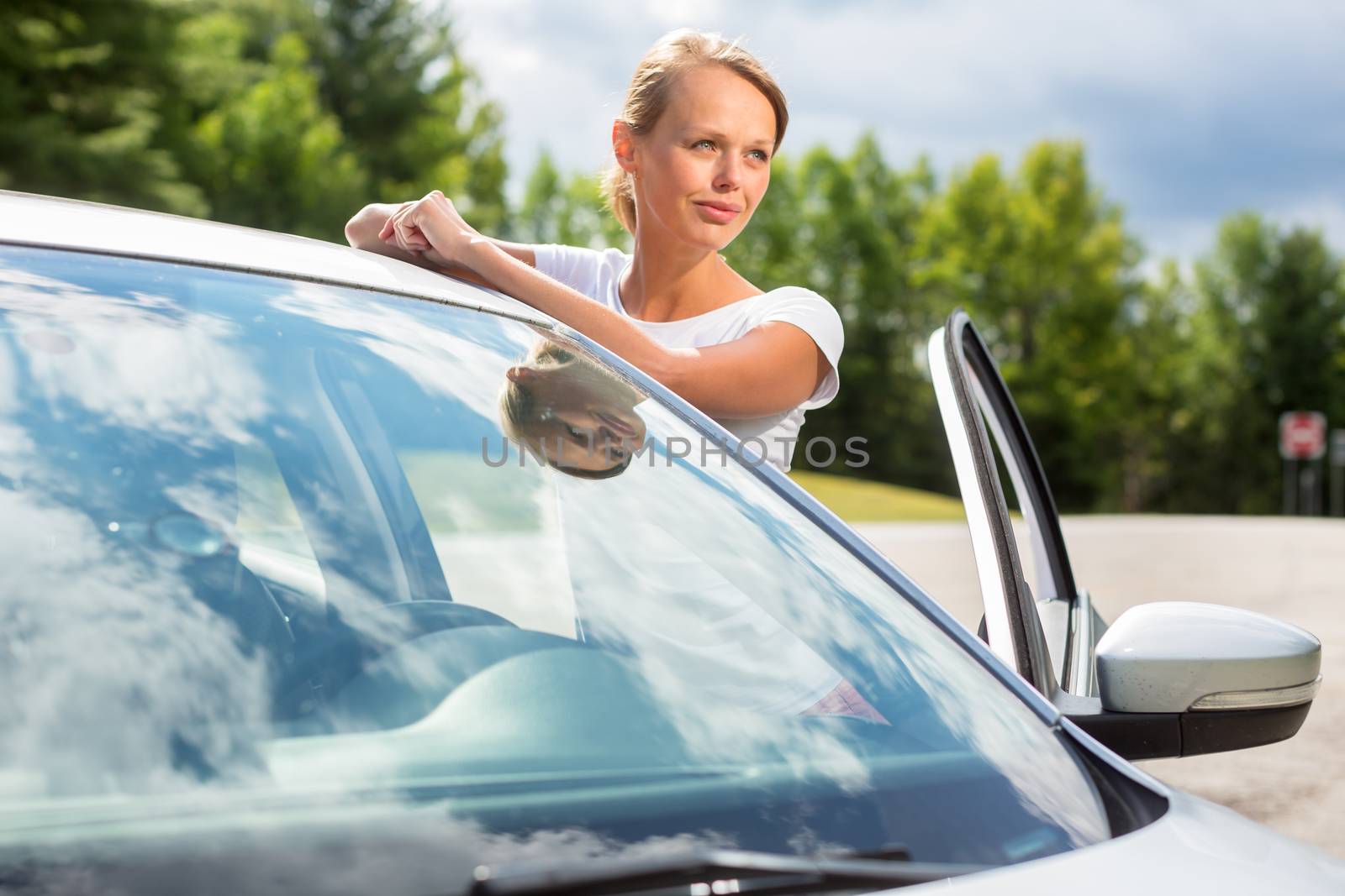 Young, attractive, happy woman standing by her car, being a proud  owner of her new vehicle