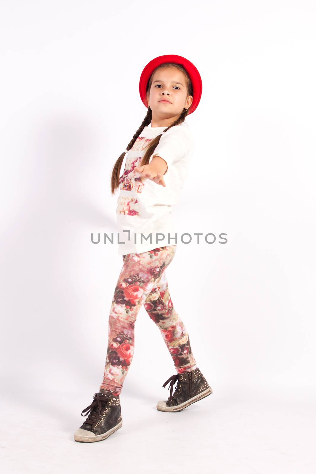 Little girl dancing with a red hat with hands on each other