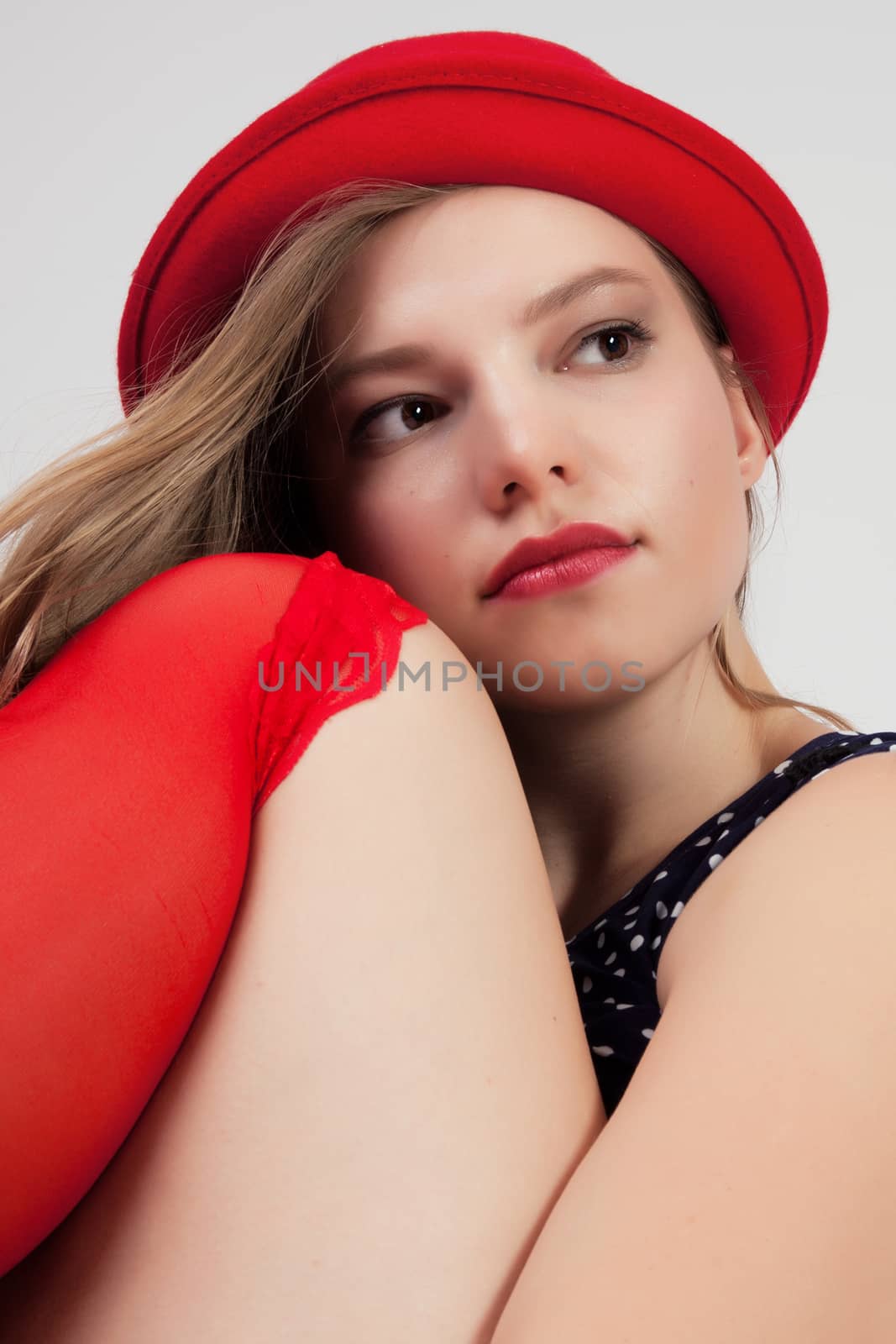 Young lady in red hat sitting with bent leg,
