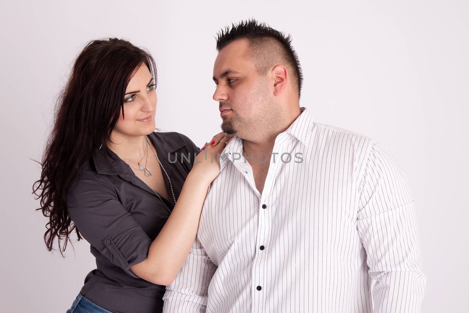 Portrait of long-haired woman rests on the shoulders of a man in a white shirt, looking at each other