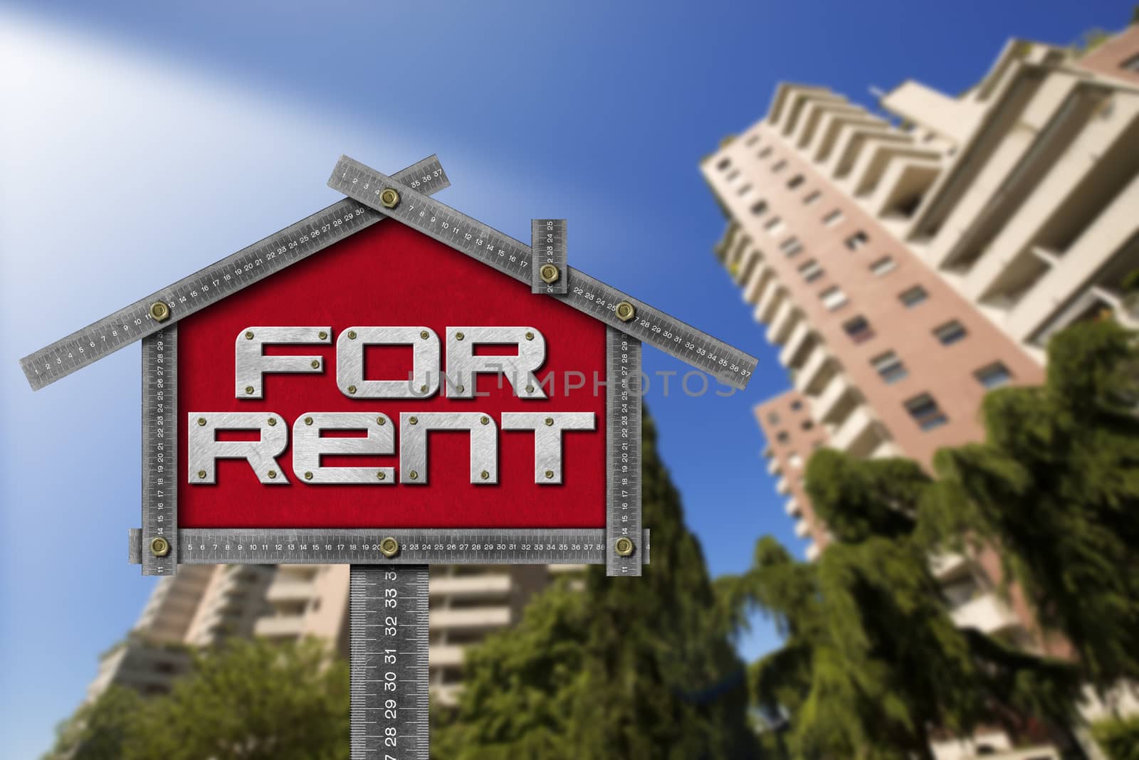 Grey metallic meter ruler in the shape of house with text for rent. For rent real estate sign with tall and blurred buildings in the background