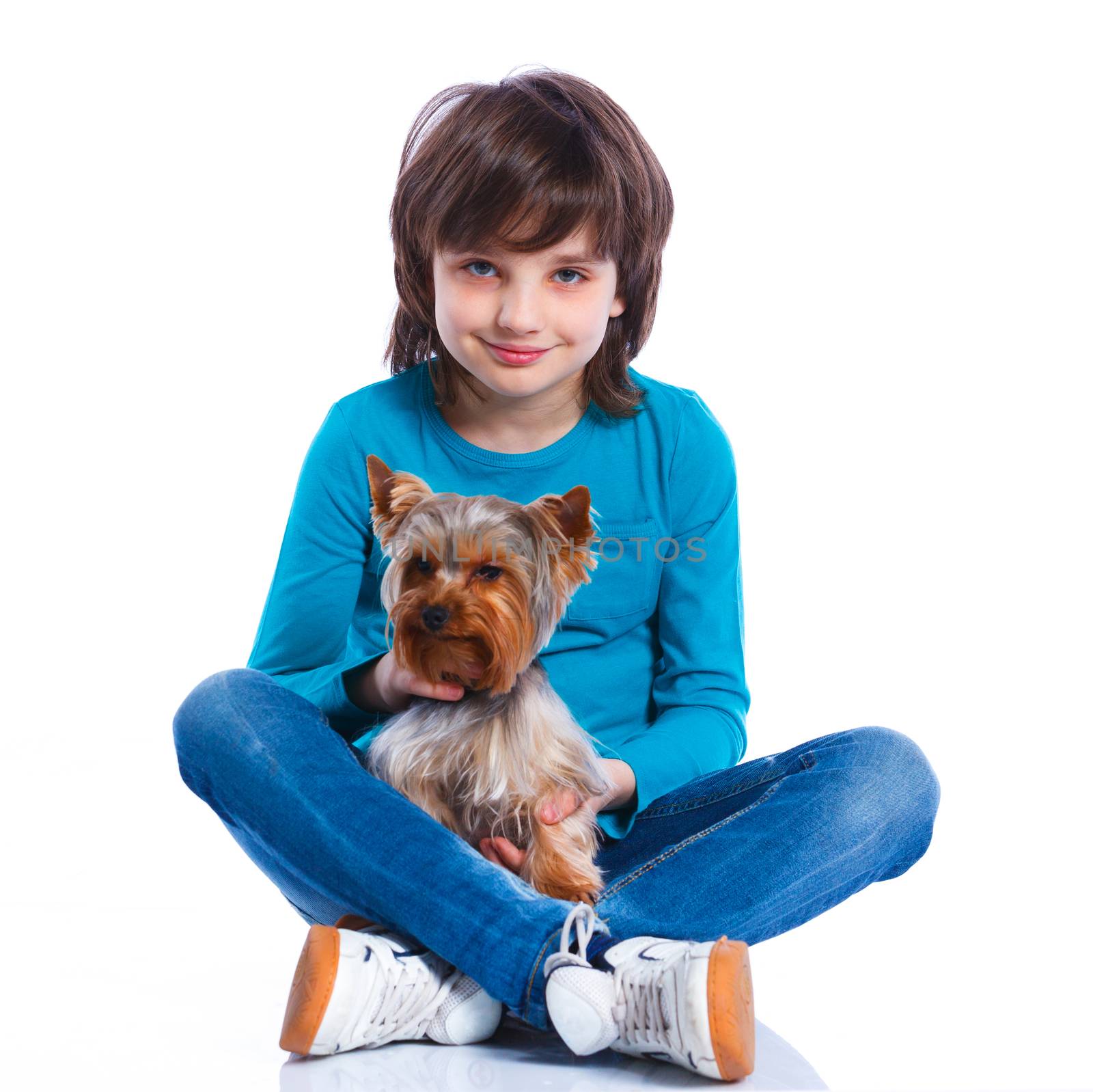 Cute boy sitting with his puppy Yorkshire terrier smiling at camera on white background