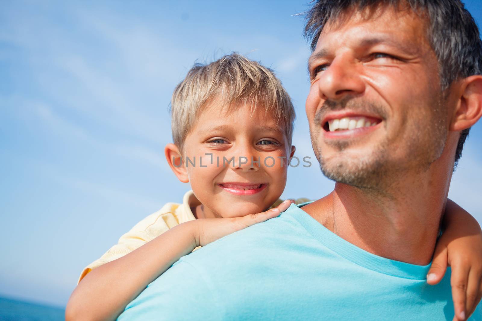 Closeup portrait og father holding son on his shoulders at the beach