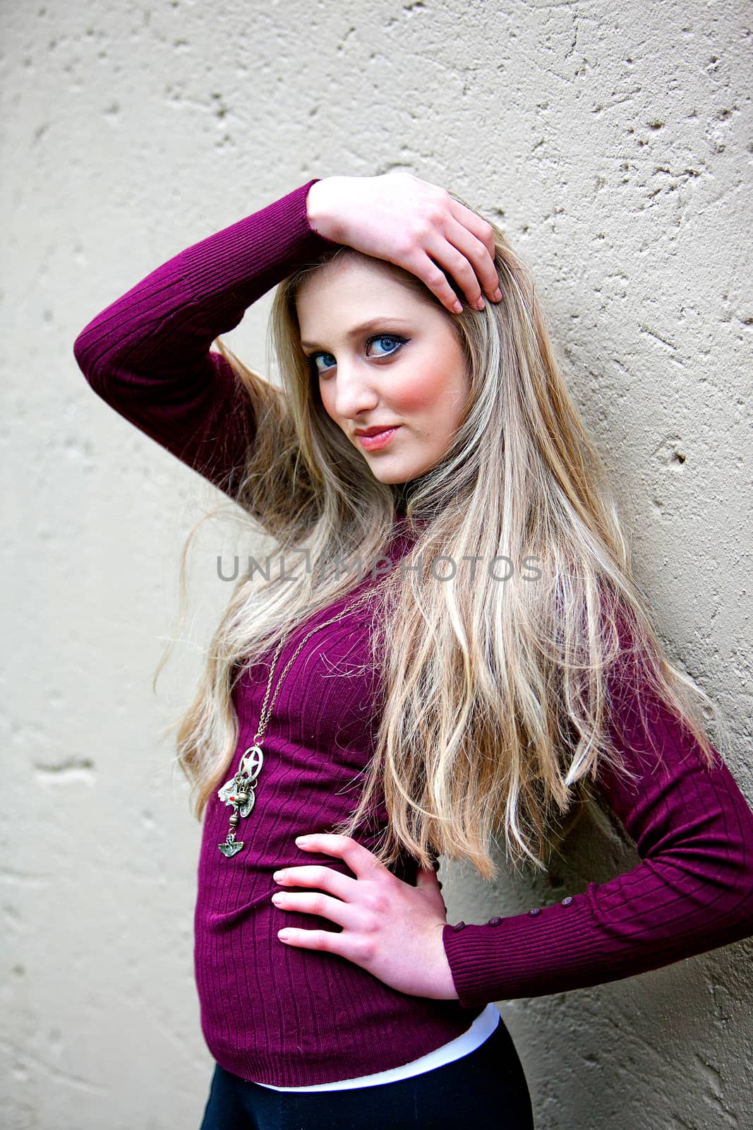 Stunning female model posing against grey textured wall