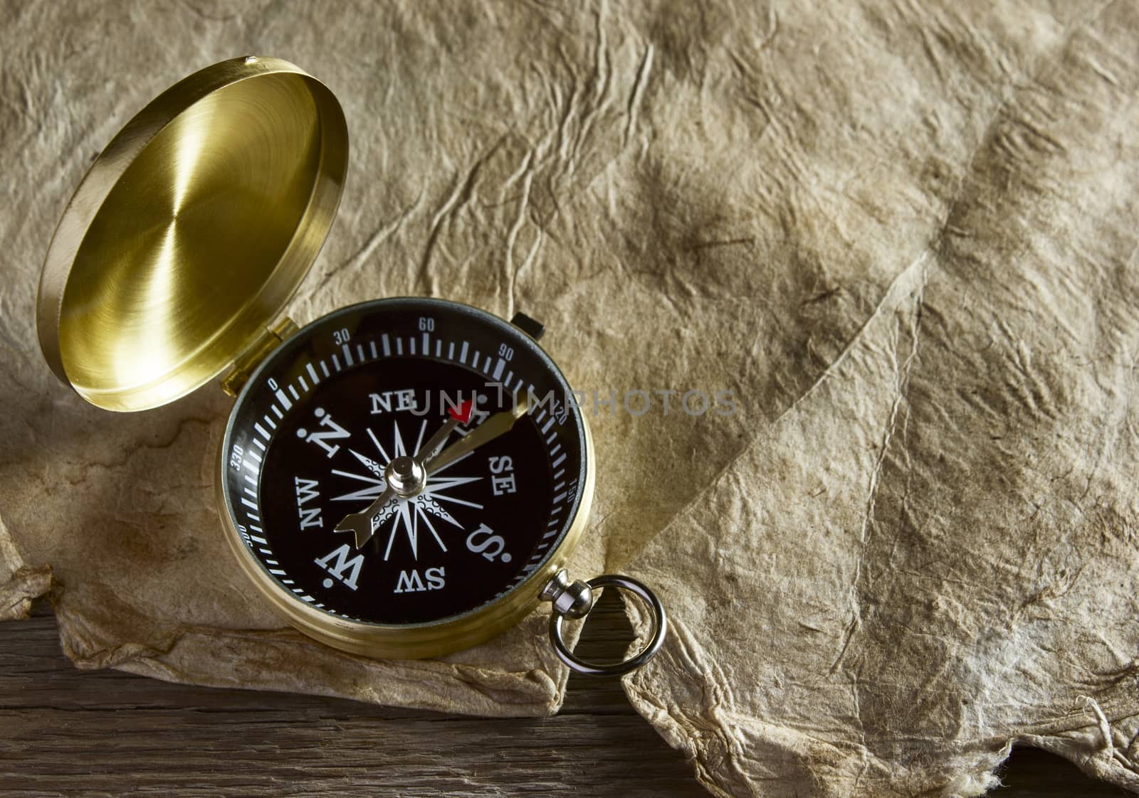 Old compass and paper on wooden background