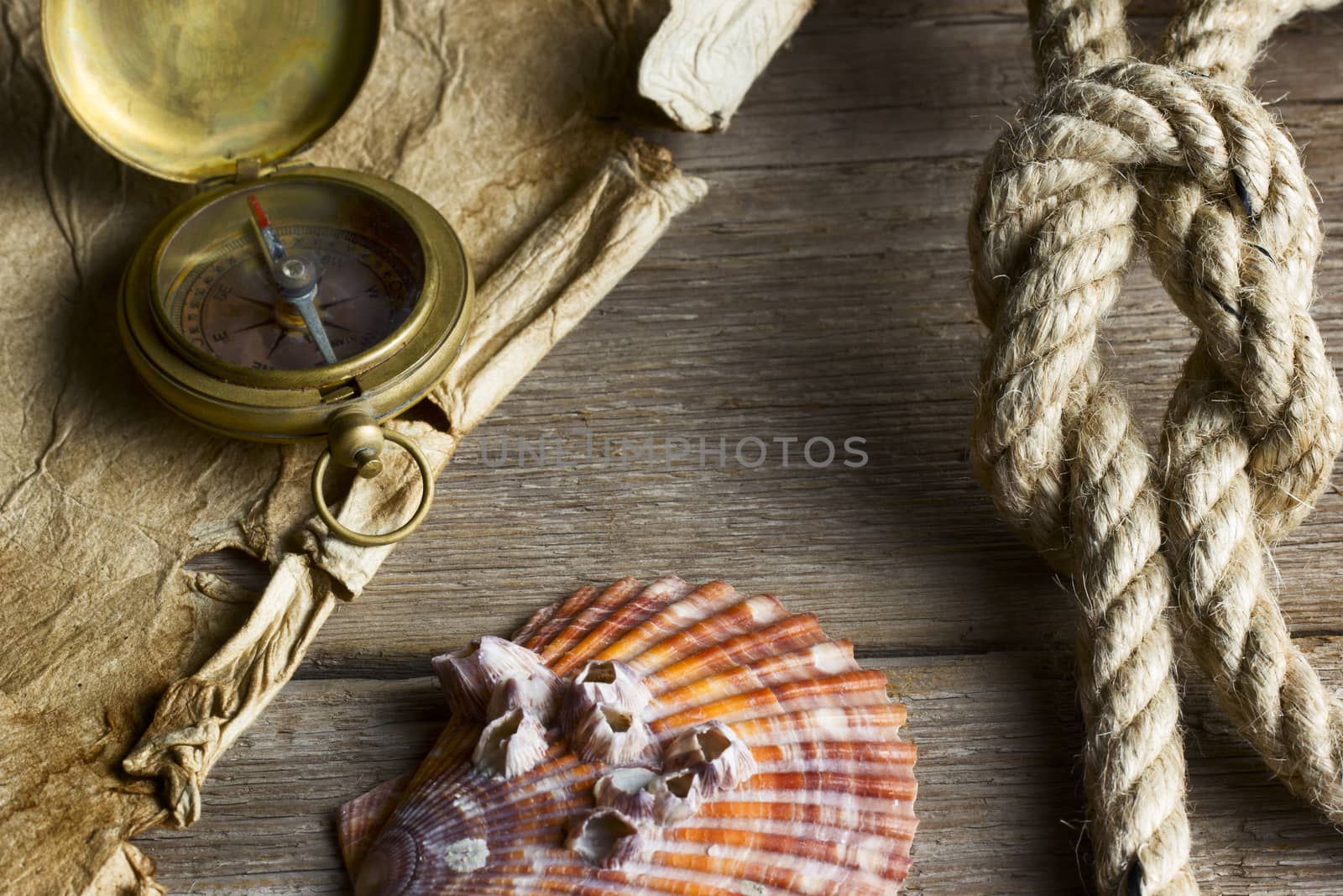 Old compass, rope and shell on wooden background