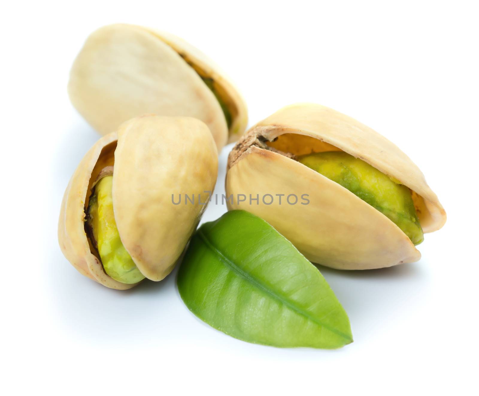 Three pistachio nuts with leaf isolated on white background