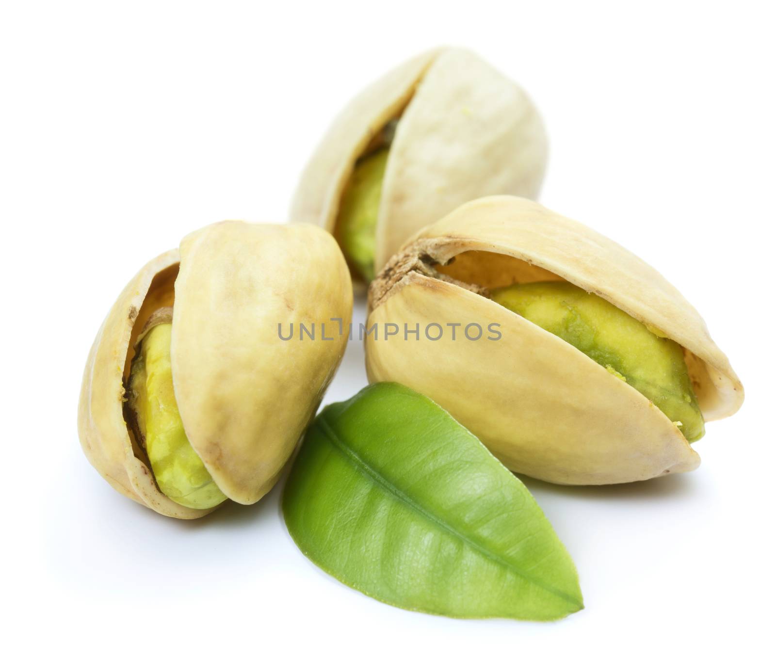 Three pistachio nuts with leaf isolated on white