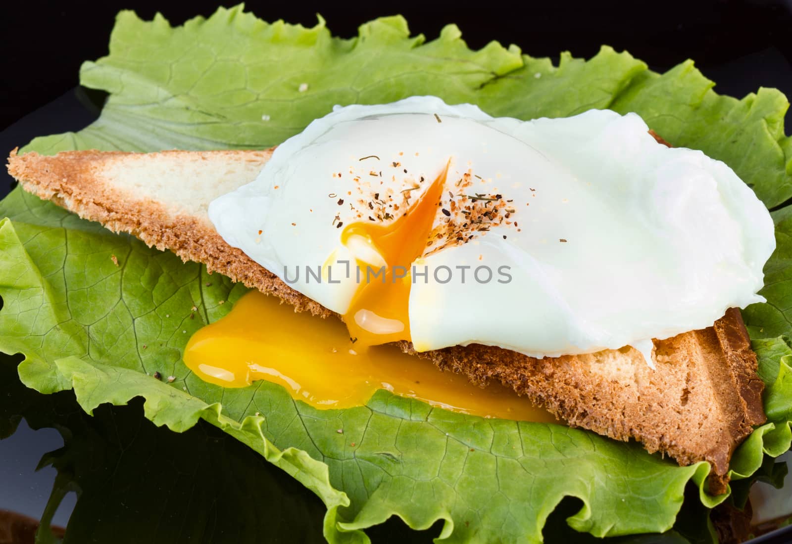 Toast with lettuce and poached egg on a black plate for breakfast. closeup 