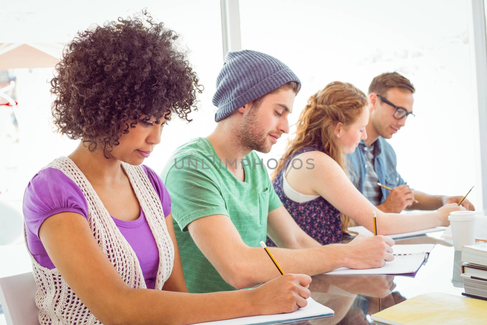 Fashion students writing on notepad at the college 