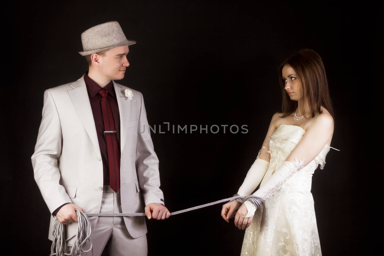 Wedding photo studio. Groom snared rope bride. fun