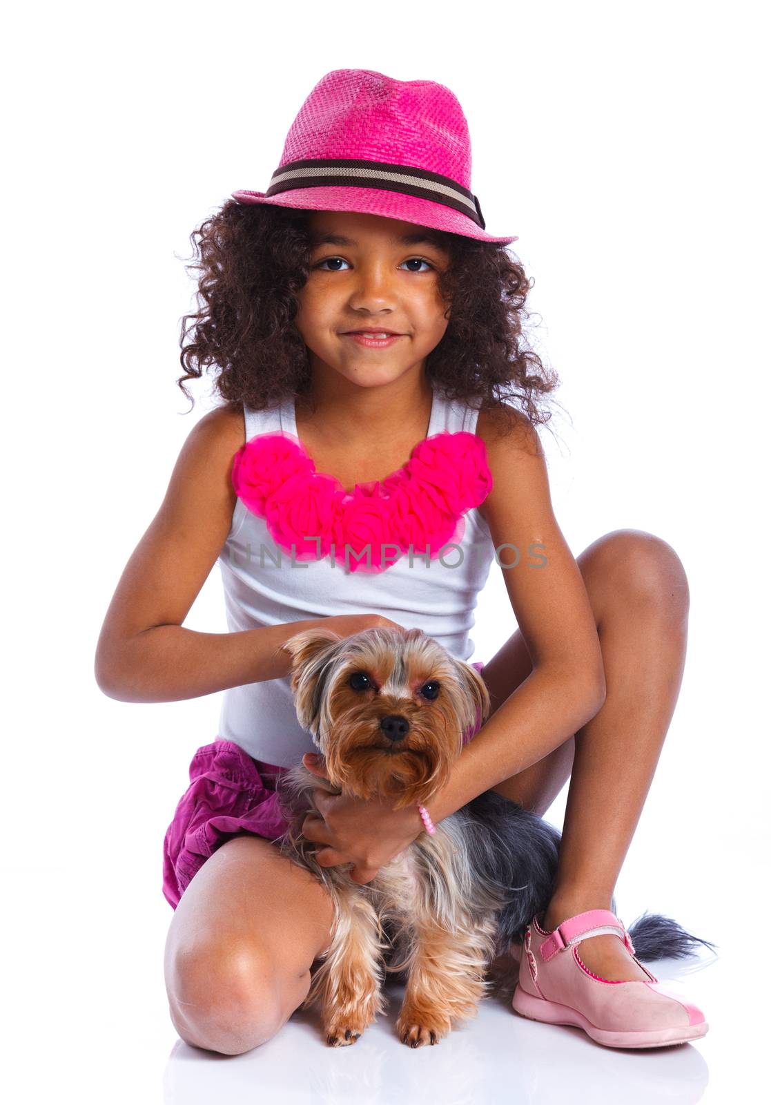 Cute little girl sitting with his puppy Yorkshire terrier smiling at camera on white background