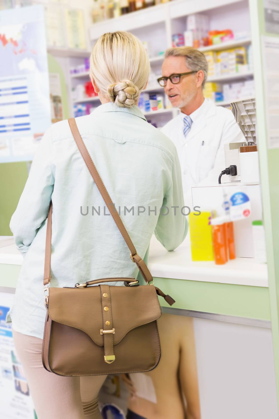 Pharmacist speaking with cheerful young customer in the pharmacy