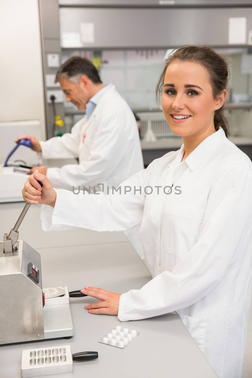 Pharmacist using press to make pills at the laboratory