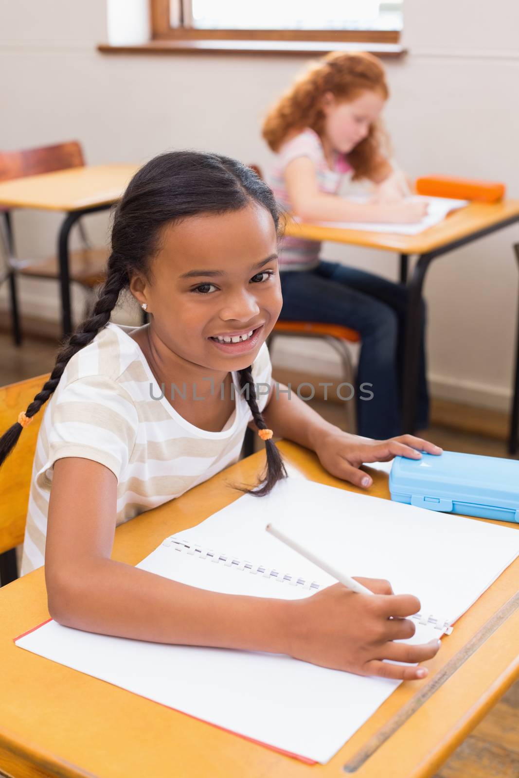 Cute pupils drawing at their desks one smiling at camera by Wavebreakmedia