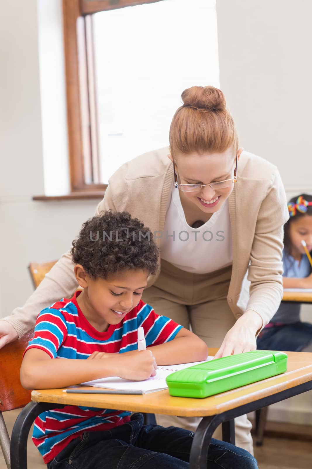 Pretty teacher helping pupil in classroom at the elementary school