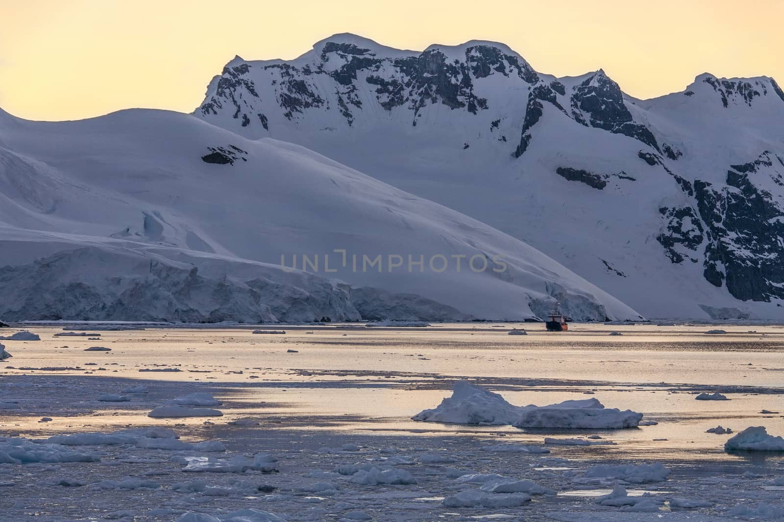 Tourist icebreaker in the dramatic scenery of the Lemaire Channel on the Antarctic Peninsula in Antarctica. Photo taken at 3am by the light of the Midnight Sun.