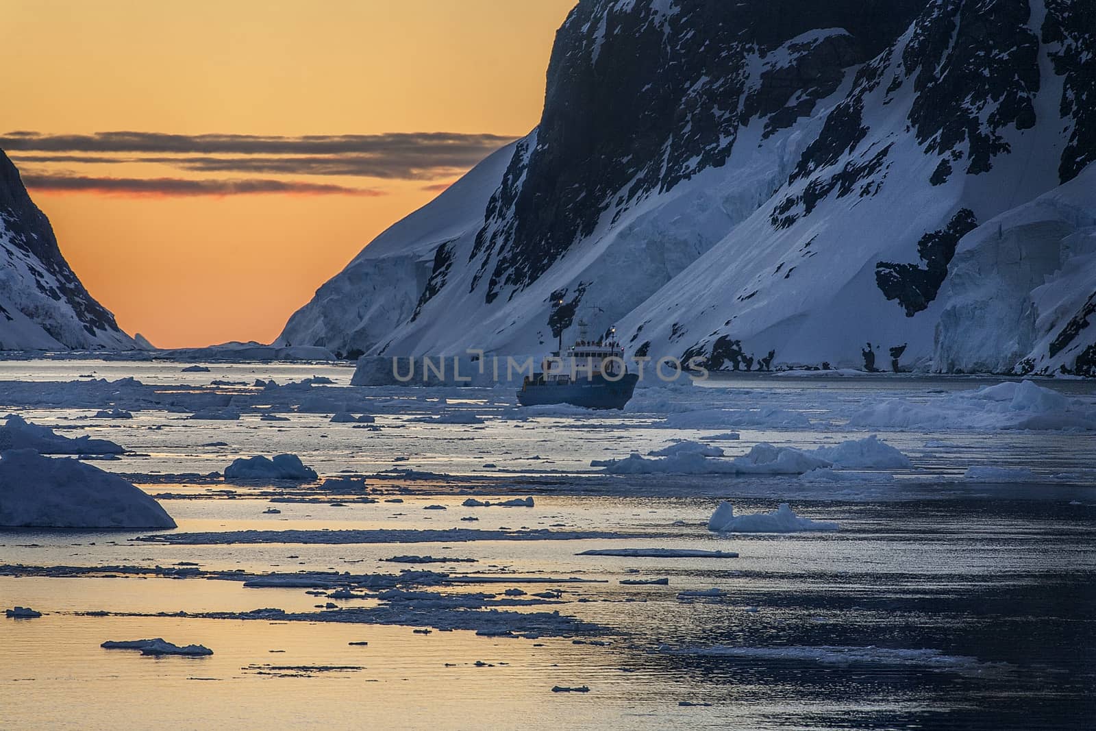 Tourist icebreaker in the dramatic scenery of the Lemaire Channel on the Antarctic Peninsula in Antarctica. Photo taken at 3am by the light of the Midnight Sun.