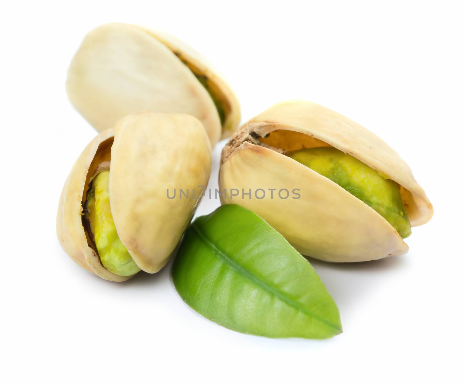 Three pistachio nuts with leaf isolated on white background
