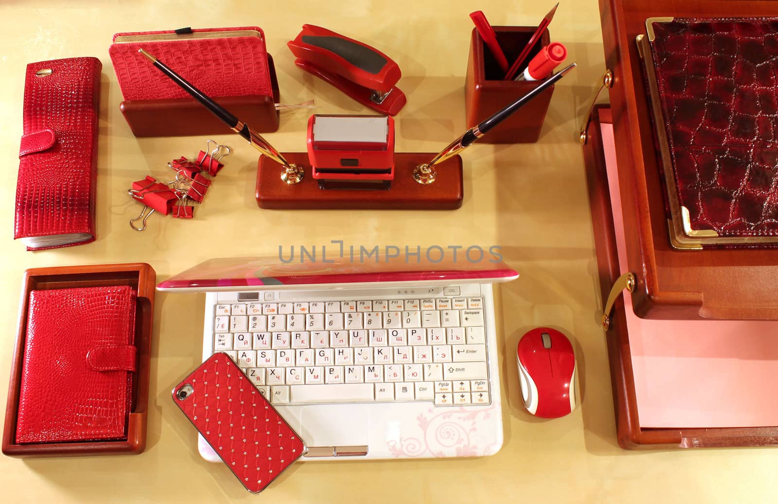 Computer, mobile phone, paper tray and stationery in red color scheme