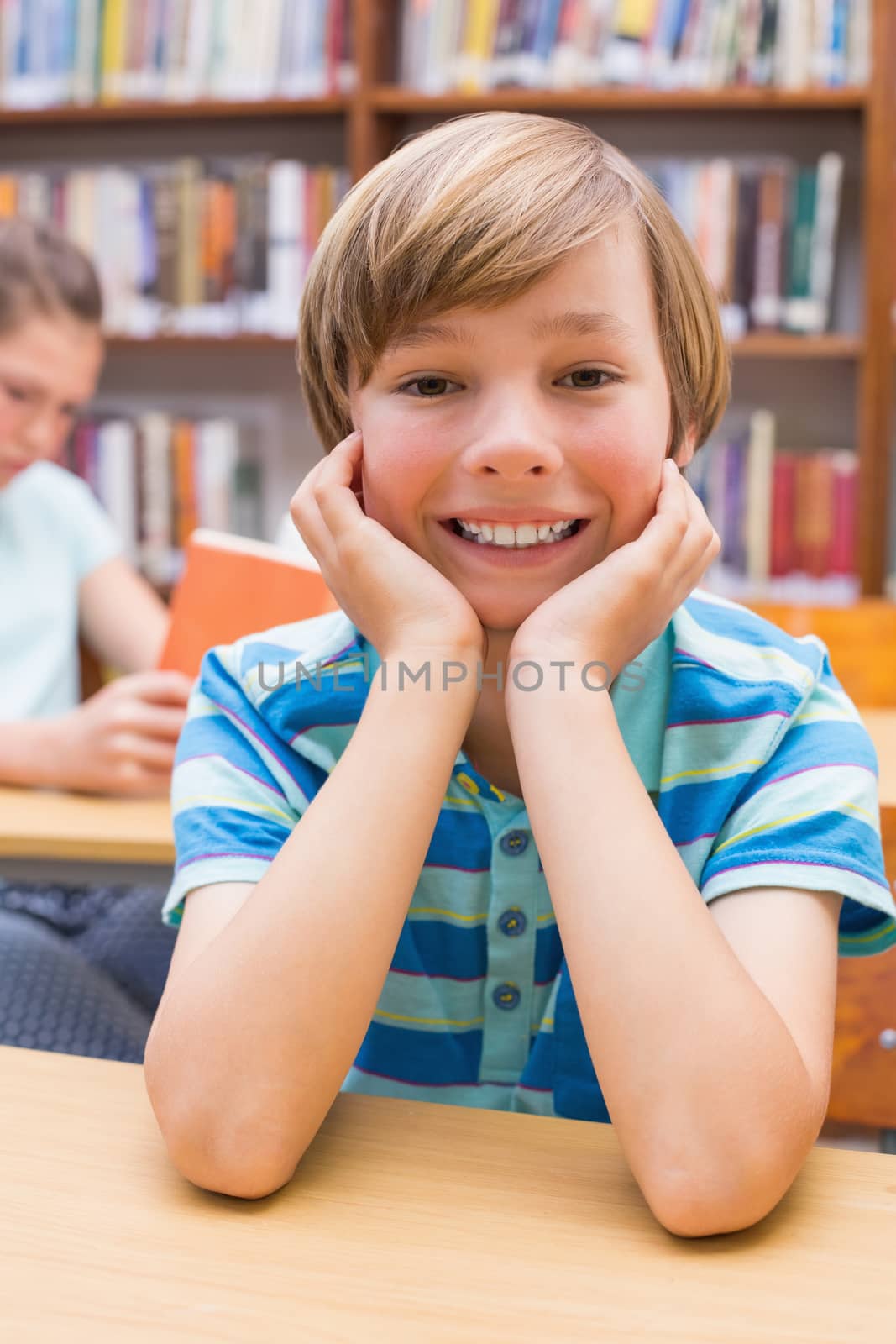 Cute pupil smiling at camera in library by Wavebreakmedia
