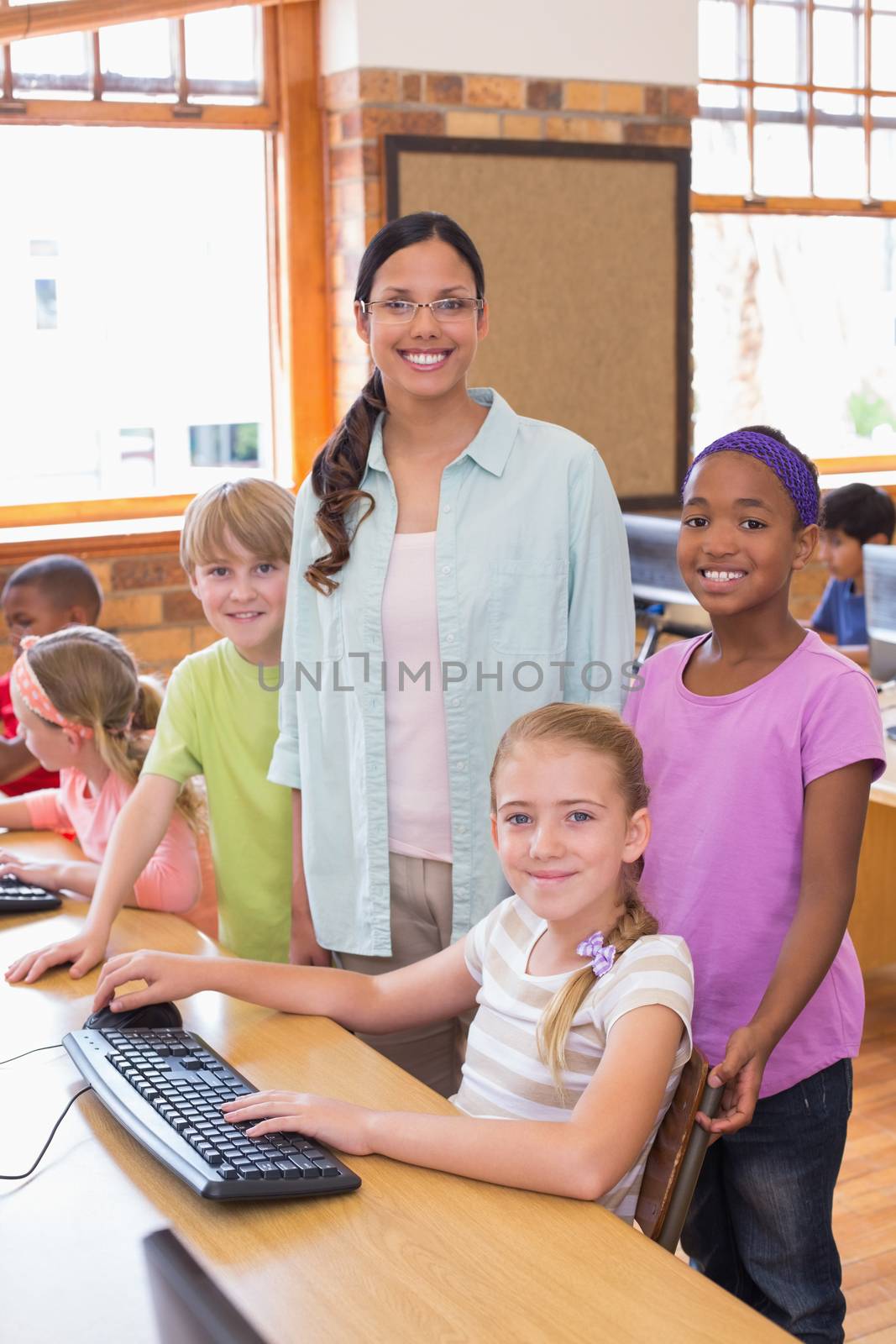 Cute pupils in computer class with teacher at the elementary school