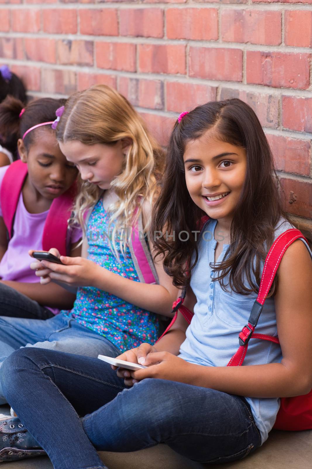Cute pupils using mobile phone at the elementary school