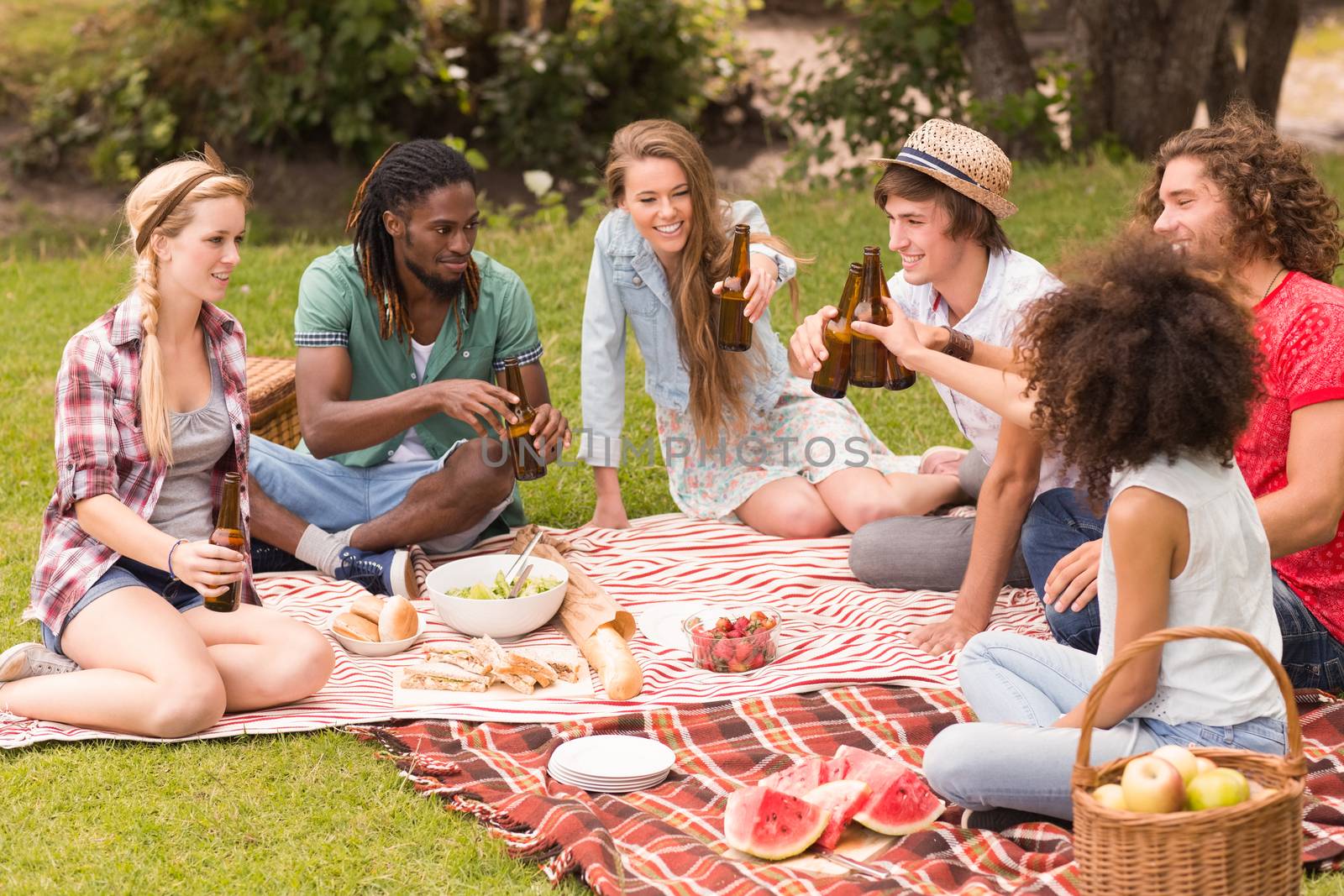 Happy friends in the park having picnic on a sunny day