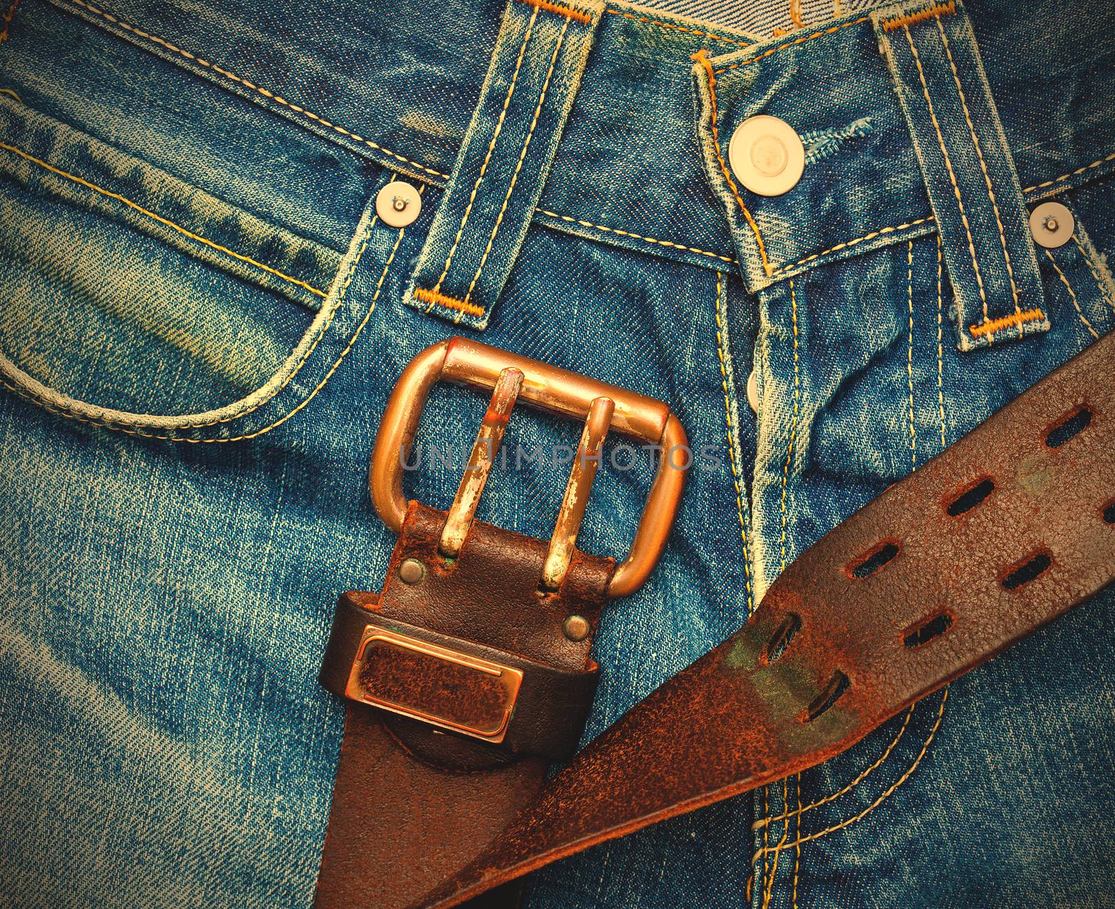 Vintage leather belt with metal buckle on old blue jeans. instagram image retro style