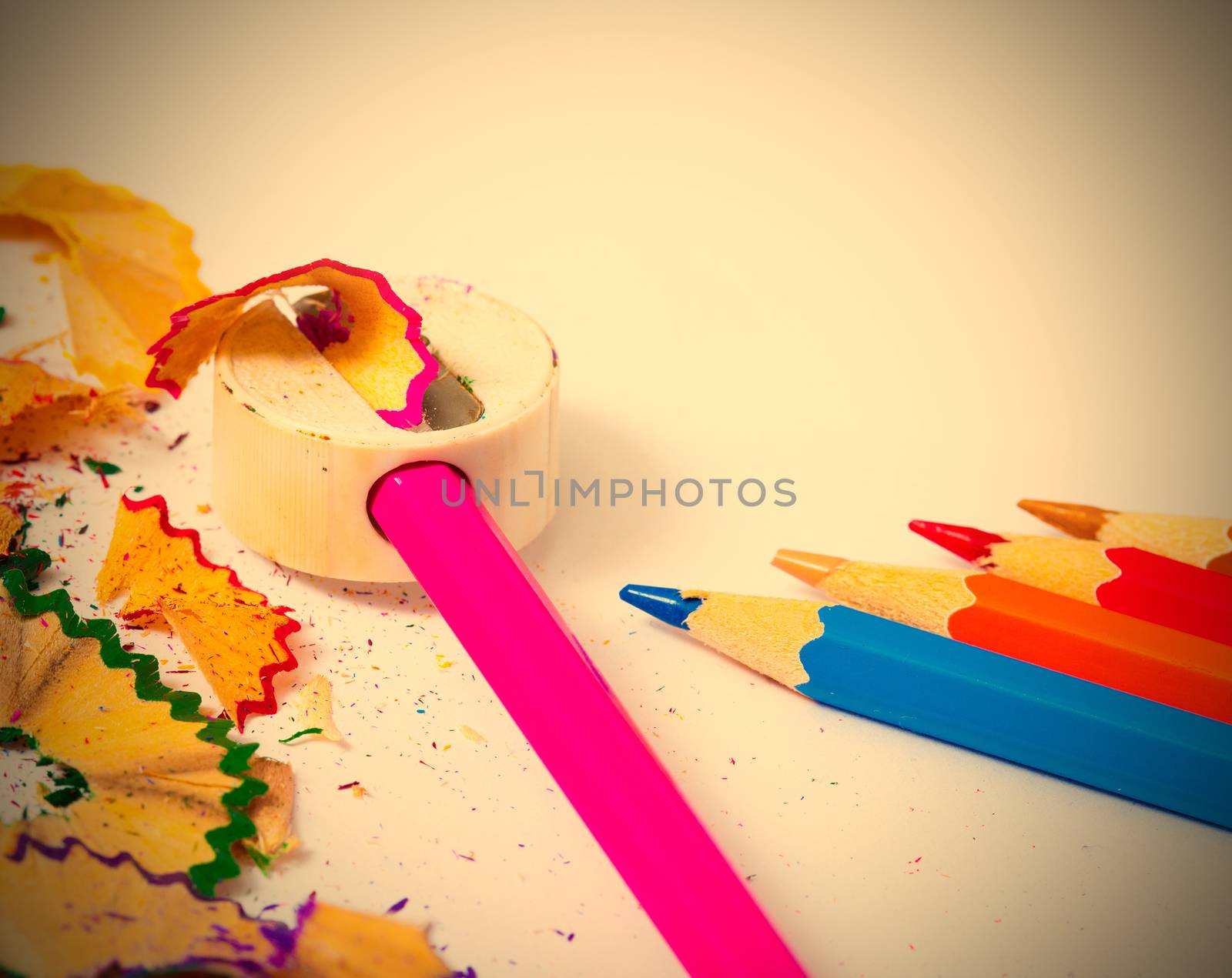 set of colored pencils, sharpener and shavings on white background with copy space. instagram image retro style