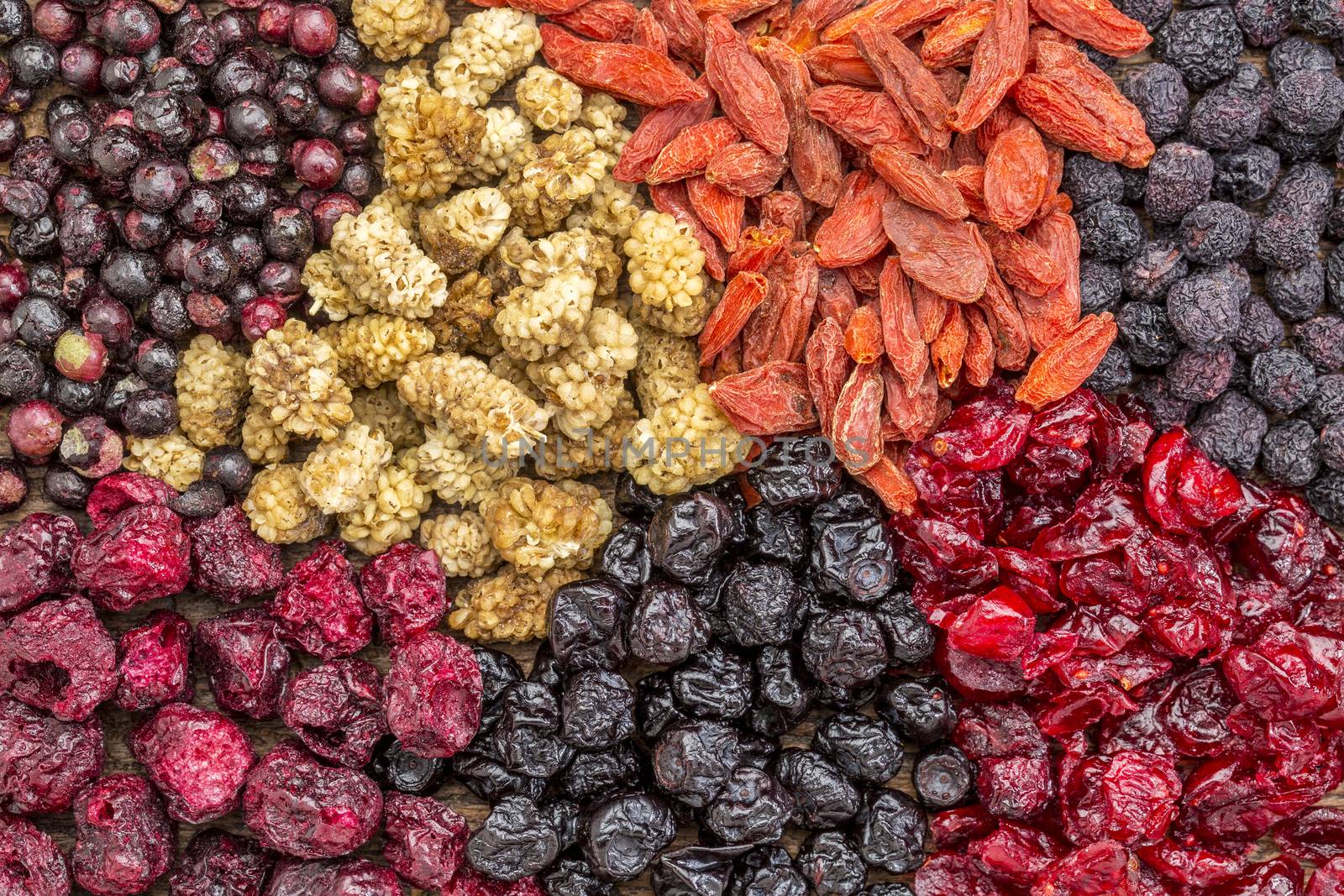 background of healthy dried superfruit berries - blueberry, mulberry, cherry, goji, elderberry, chokeberry, and cranberry