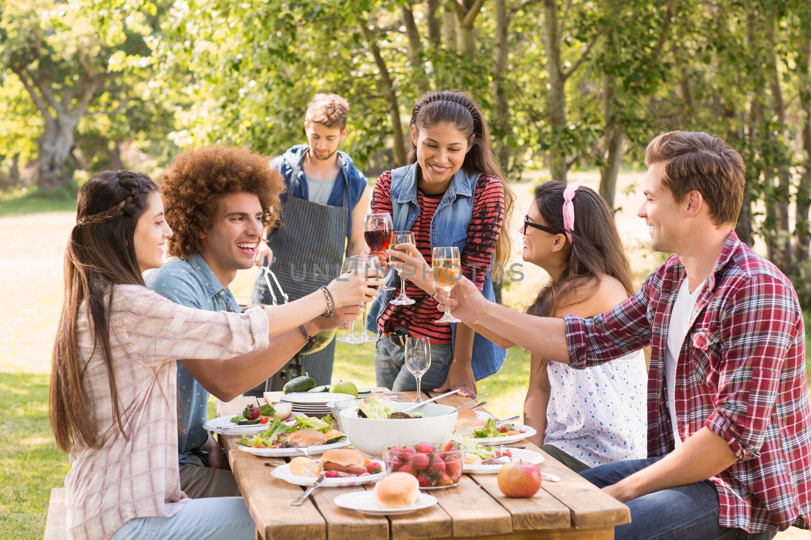 Happy friends in the park having lunch on a sunny day